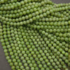 A close-up pile of small, round, light green beads with a glossy finish, filling almost the entire frame.