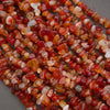 Close-up of a string of red and orange gemstone beads on a gray surface