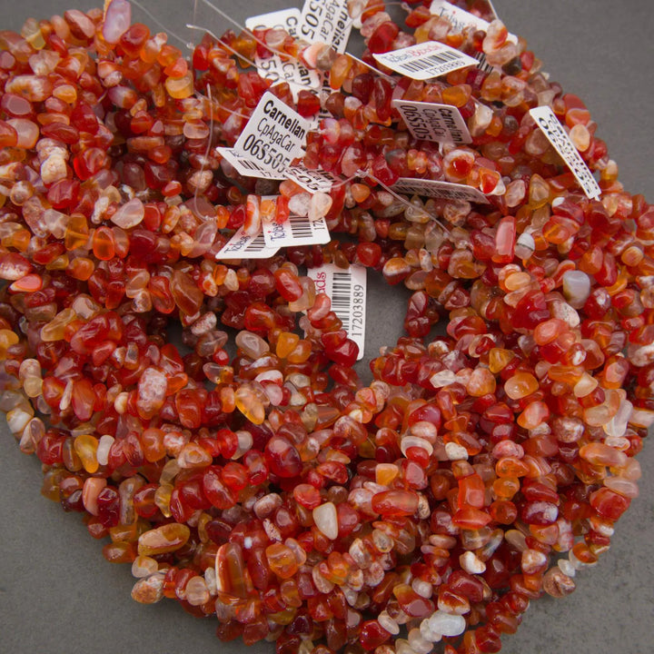 Necklace made of red and orange stones with price tags on a gray background