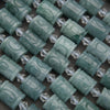 Teal cylindrical beads with clear crystal-like accents on a dark background