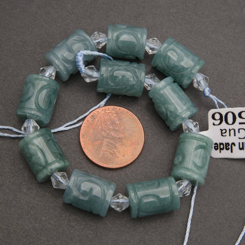 Green jade beads with crystal accents on a string, next to a penny for scale, on a gray background.