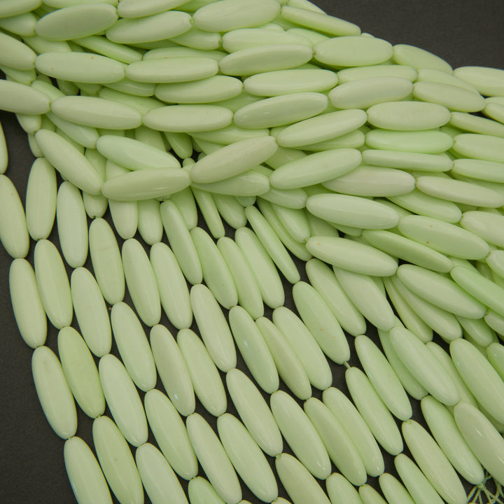 Close-up of light green oval beads on a dark background