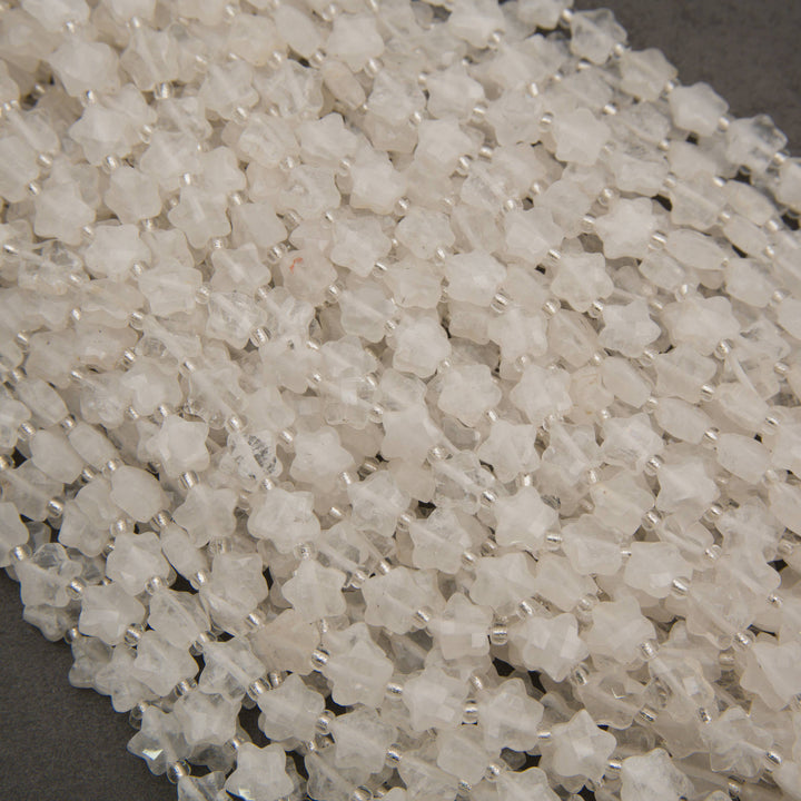 A heap of faceted clear quartz star bead strands in frosty white and water clear with silver seed bead spacers