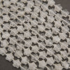 Rows of faceted clear quartz star beads on a gray background, frosty white to water clear