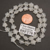 A strand of faceted clear quartz star beads coiled around a penny for scale