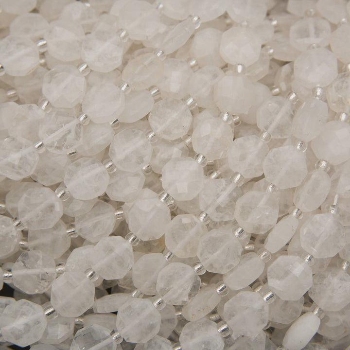 Close-up of faceted clear quartz beads displaying geometric octagonal cuts and frosty white coloration.