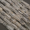 Natural clear quartz tube beads featuring transparent crystal surfaces, elongated shapes, and delicate internal inclusions.