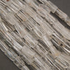 Close-up of polished clear quartz gemstone tube beads showcasing excellent transparency and natural internal veils.