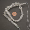 Transparent clear quartz gemstone beads featuring natural fractures, cloudy inclusions, and occasional earthy mineral markings.