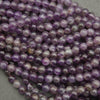 Close-up of a string of purple beads on a gray background