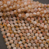 A pile of round, translucent peach and orange beads with natural inclusions, photographed close-up on a dark gray background.