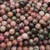 Close-up of smooth round cobalto calcite beads in dusty rose, magenta and olive green with dark specks