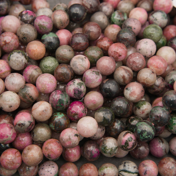 Close-up of smooth round cobalto calcite beads in dusty rose, magenta and olive green with dark specks