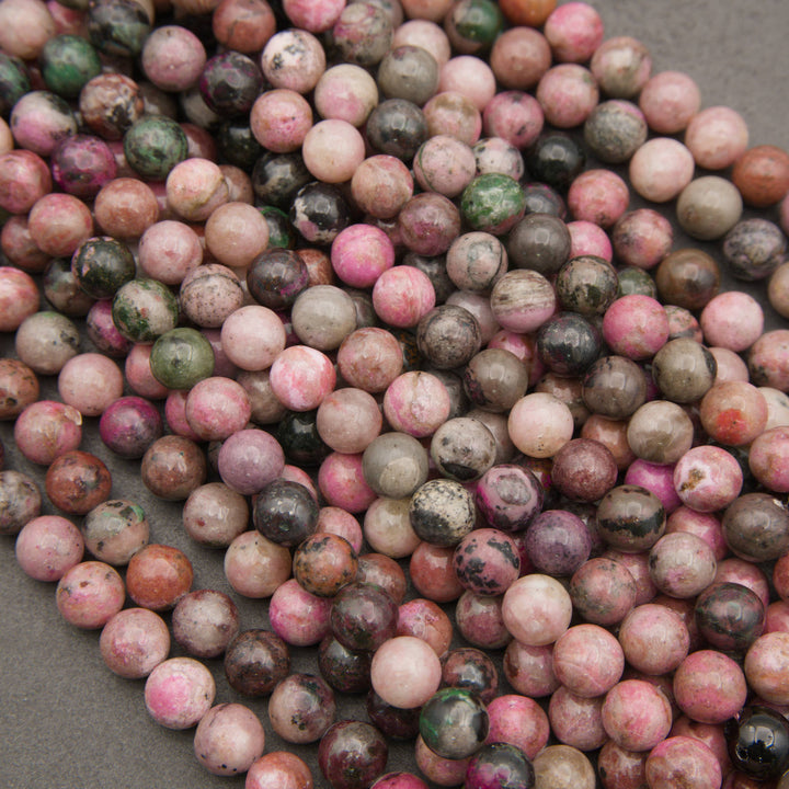 A heap of smooth round cobalto calcite bead strands in pink, mauve, tan and green