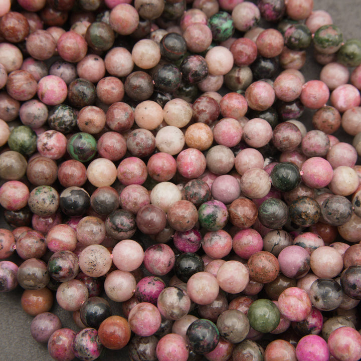 Strands of smooth round cobalto calcite beads in dusty rose and hot pink with dark matrix