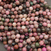Strands of smooth round cobalto calcite beads in dusty rose and hot pink with dark matrix