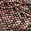 Rows of smooth round cobalto calcite beads on a gray background in pink, brown and olive green