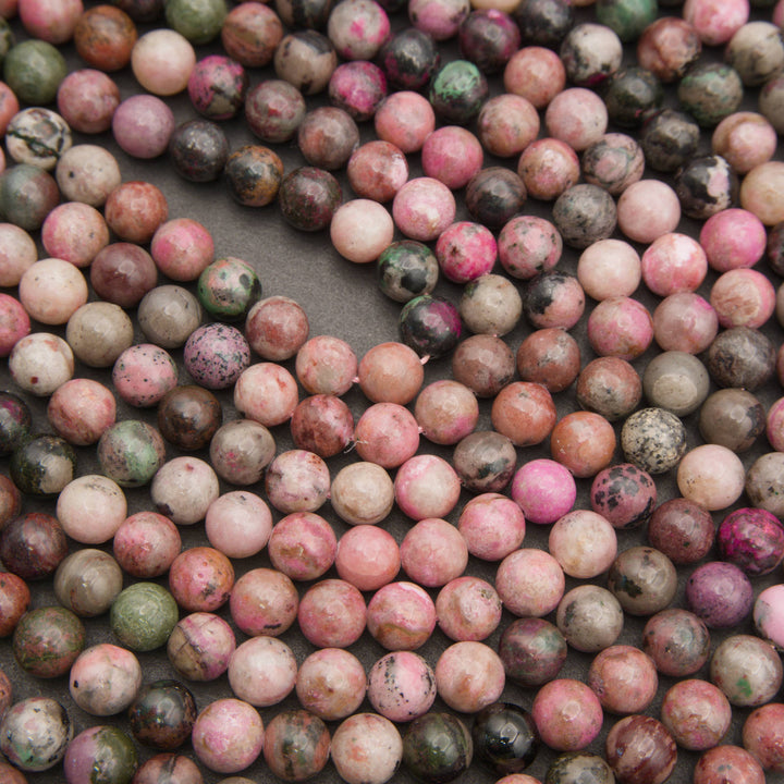Smooth round cobalto calcite bead strands laid in curving rows, mixing pink, magenta and mauve