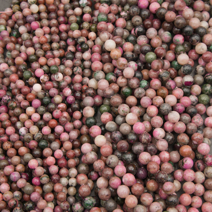 Many strands of smooth round cobalto calcite beads fanned out in pink, mauve and green