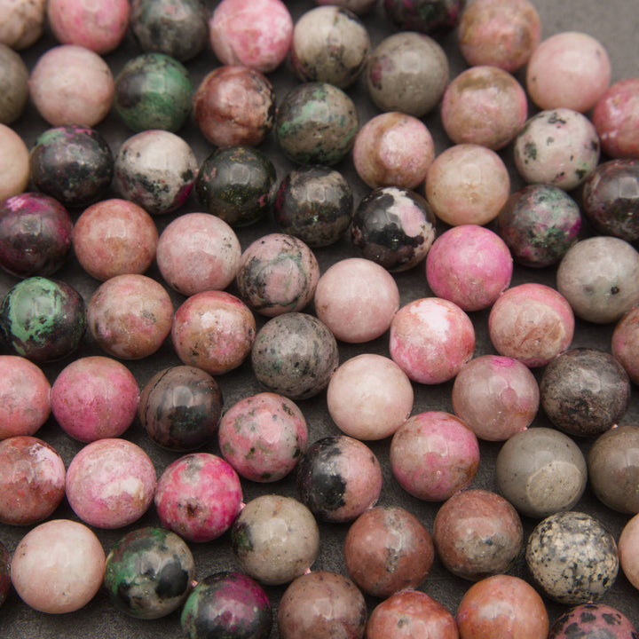Close-up of polished cobalto calcite beads showing hot pink, rose, tan and green patches with black specks