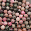 Close-up of polished cobalto calcite beads showing hot pink, rose, tan and green patches with black specks