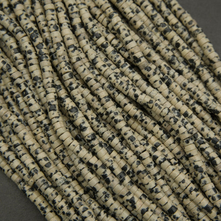 Close-up of dalmatian jasper disc beads showing natural black inclusions on a beige base.