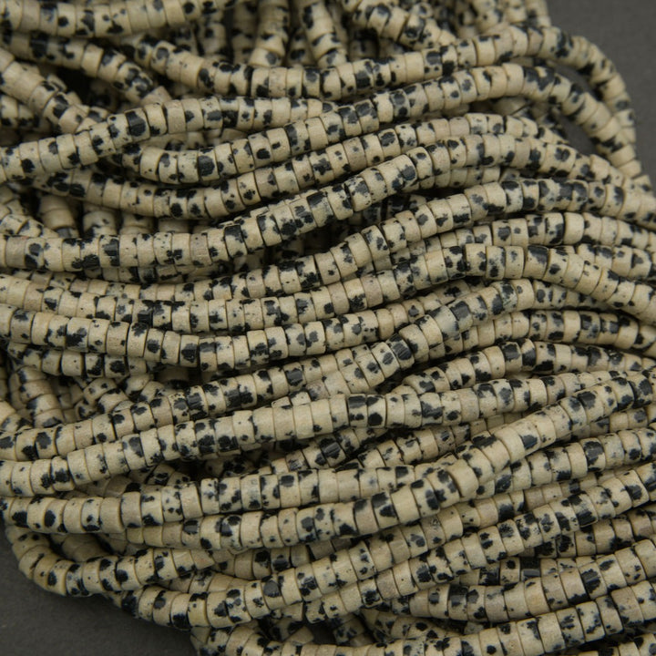 Detailed view of dalmatian jasper heishi bead strands with speckled stone pattern.