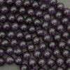 Close-up of purple beads on a string against a neutral background