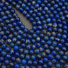 Close-up of many small round blue beads with white speckling, arranged on a dark gray surface.