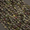 A heap of faceted dragon's blood jasper oval bead strands in mottled green and red