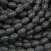 Black lava stone oval beads with a matte finish and naturally porous volcanic texture for jewelry making.