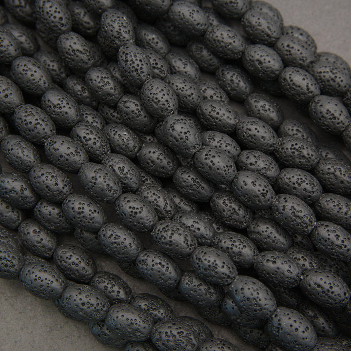 Close-up of black lava rock oval beads featuring elongated shapes and distinctive volcanic pitting.