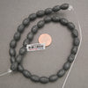 Natural black lava stone oval gemstone beads with a textured matte finish for handmade bracelets and necklaces.