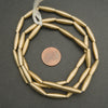 Gold beads on a string with a penny for scale on a gray background