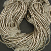 Close-up of beige woven material with tassels on a dark background