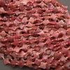 Pink strawberry quartz beads with faceted surfaces, subtle translucency, and rosy-red coloration.