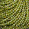 A close-up pile of faceted green gemstone beads with natural marbled inclusions.