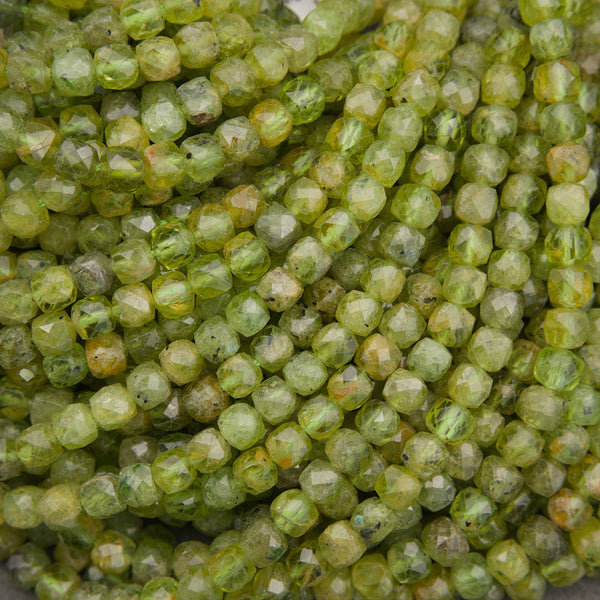 A close-up pile of faceted green gemstone beads with natural marbled inclusions.