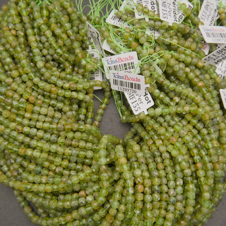 Coiled strands of faceted green beads with white price tags attached, photographed closely on a neutral surface.