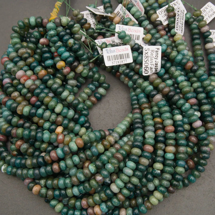 Green and multicolored beads on a gray surface with labels.
