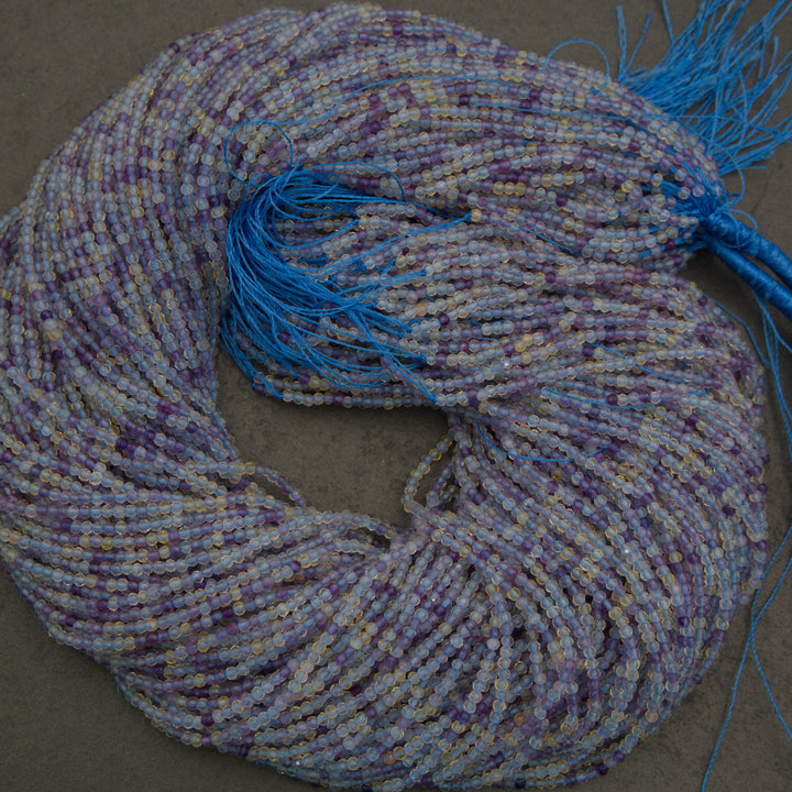 Coiled multicolored beaded yarn with blue tassel on a gray background