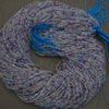 Coiled multicolored beaded yarn with blue tassel on a gray background