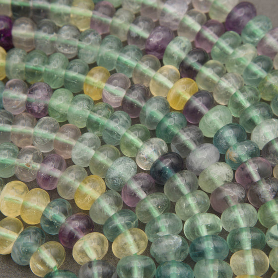 Smooth multicolor fluorite beads displaying shades of mint green, lavender, aqua blue, and golden yellow.