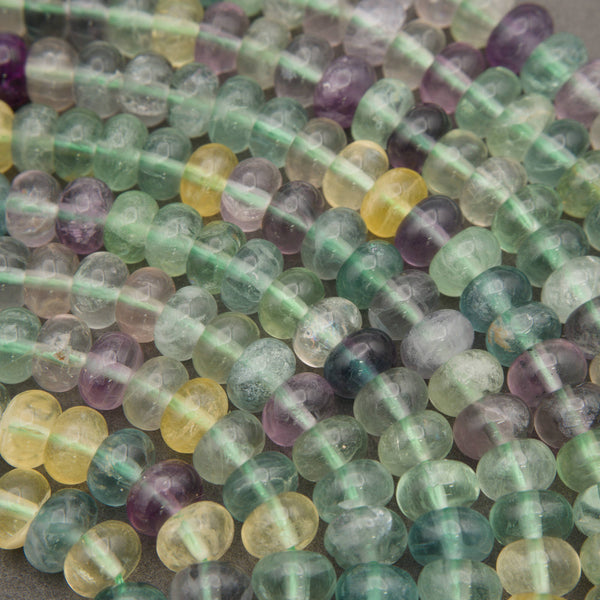 Smooth multicolor fluorite beads displaying shades of mint green, lavender, aqua blue, and golden yellow.