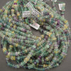 Strands of multicolor fluorite beads featuring soft seafoam green, deep purple, and pale yellow hues.