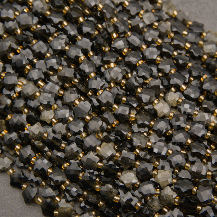 A heap of faceted golden obsidian star bead strands in smoky black and charcoal with gold seed bead spacers