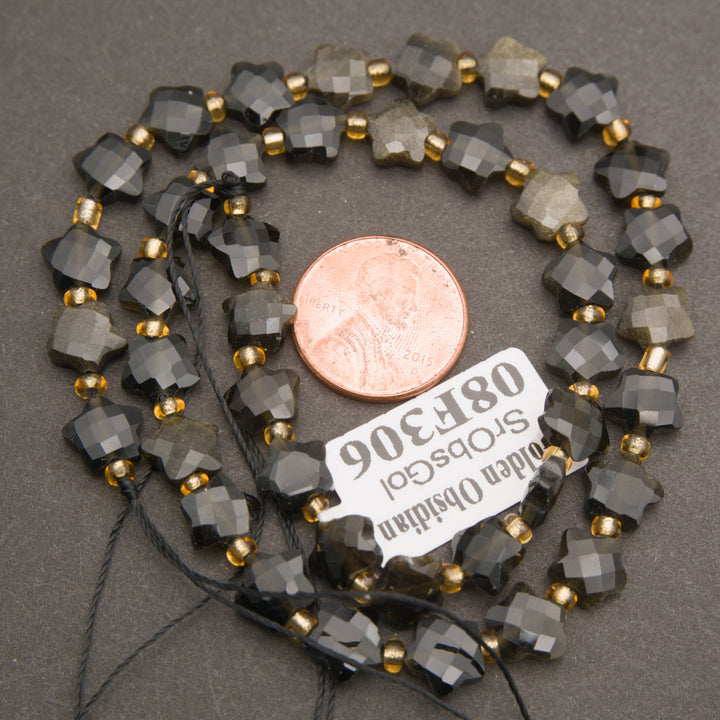 A strand of faceted golden obsidian star beads coiled around a penny for scale