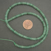 Green bead string with a penny for size comparison on a gray background