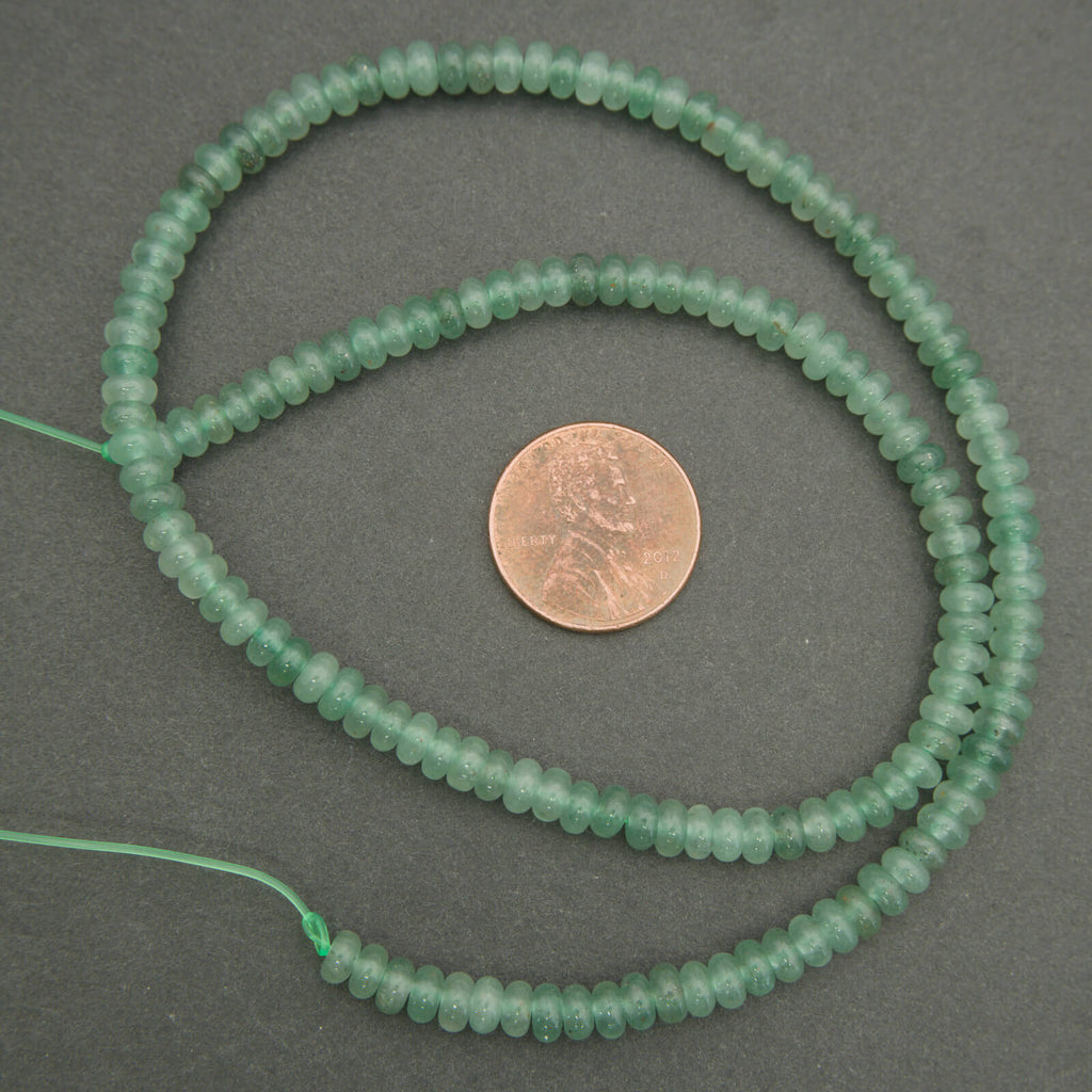 Green bead string with a penny for size comparison on a gray background