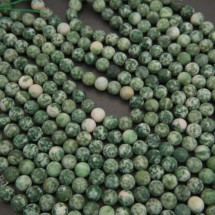 Close-up of green and white marbled beads on a dark background